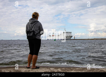 merchant ship entering the Baltic port in Poland,woman on the sea shore Stock Photo