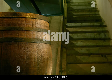 wooden barrel on a dark background, in a workshop, in an old room. production of barrels for cognac and wine, in a low key Stock Photo