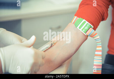 Young woman on the collection of blood in the hospital laboratory. Blood tests for disease and prevention Stock Photo