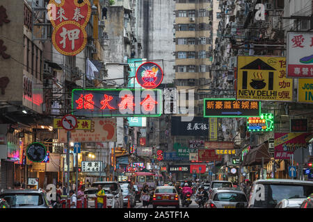 Vibrant neon signs and bright streetlights glowing above the busy night traffic  in Kowloon, Hong Kong - China. Stock Photo