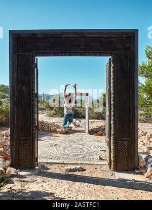 landscape and doors of Cala LLentia in Ibiza, Baleares, Spain.Woman with her back jumping between the two doors Stock Photo