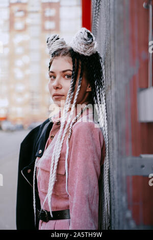 Portrait of beautiful cool girl with Senegalese pigtails and dreadlocks over red wall Stock Photo