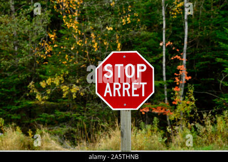 A red and white bilingual stop sign on an intersection in rural New Brunswick Canada Stock Photo