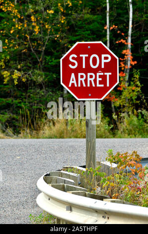 A vertical image of a bilingual stop sign situated in rural New Brunswick Canada. Stock Photo