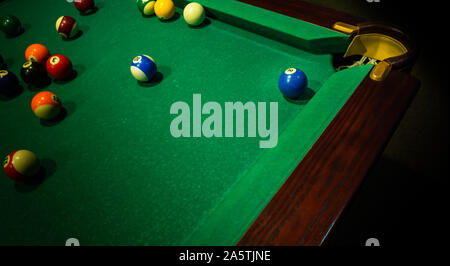 Few colorful numbered balls on green table, near its corner and ball pocket.. Horizontal background with equipment for Americal billiard cue sport gam Stock Photo