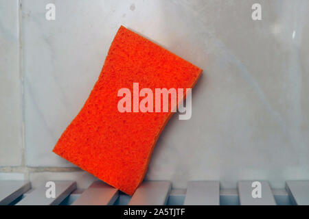 Orange sponge on a table in the sink. Stock Photo