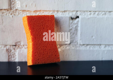 Orange sponge on a table in the sink. Stock Photo