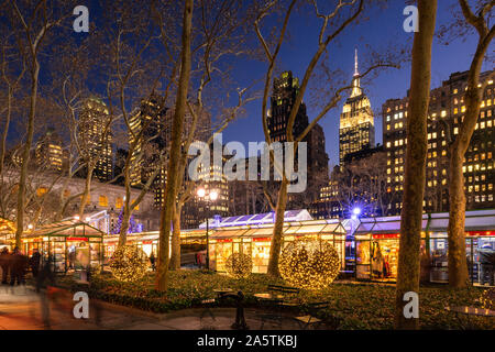 Bryant Park Winter Village (Christmas Market) in evening with the Empire State Building in the background. New York City, NY, USA Stock Photo