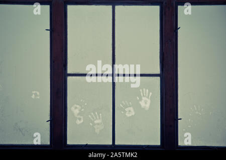 Window in the room covered with frosty mosaic in winter. Frost patterns on glass. Handprints Stock Photo