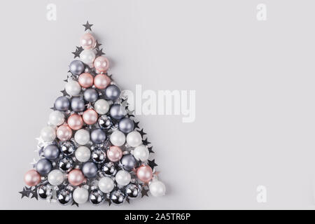 Christmas tree made of stars, confetti, silver pastel balls on grey background. Xmas composition. Flat lay, top view, copy space. Holiday Greeting car Stock Photo