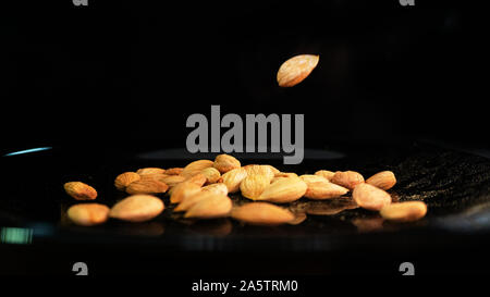 Almond and apricot grains, on the varnished plate falling seeds. The use of almonds in the culinary industry and advertising trade Stock Photo