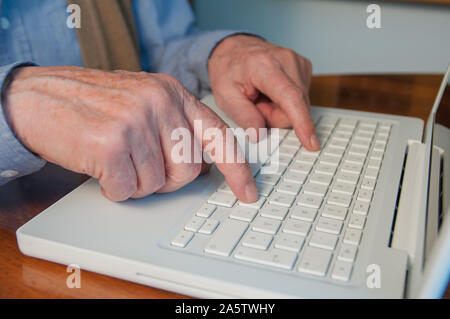 Senior hands typing on laptop keyboard Stock Photo