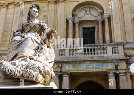 Statue of Queen Victoria, wearing a shawl of Maltese lace, in front of National Library of Malta, commonly known as the Bibliotheca, at Republic Squar Stock Photo
