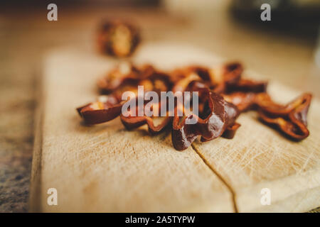 Chocolate Habanero pepper (Capsicum chinense) slices on a wood cutting board. Healthy and really hot chili peppers. Blurry background. Stock Photo