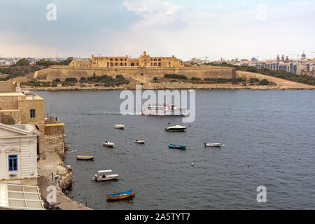 View of Fort Manoel from Valletta, with several boats and ferry in front. It is a star fort on Manoel Island in Gzira, Malta, built in the 18th centur Stock Photo