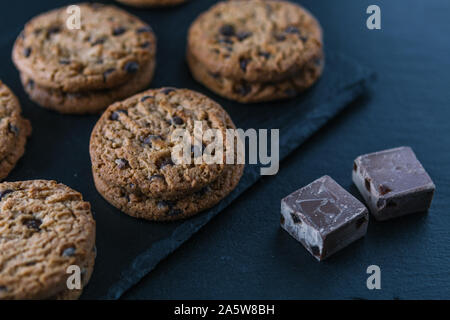 Handmade chocolate chip cookies and cocoa pieces on a chalkboard table. Stock Photo