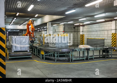 Robot Hand manipulator packaging factory products from conveyor into container. Stock Photo