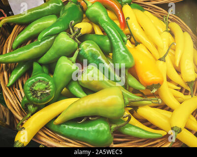 Fresh green and yellow peppers on a wicker plate in the store with lens flare. For any purprose. Stock Photo