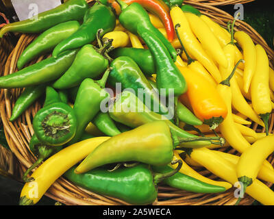 Fresh green and yellow peppers on a wicker plate in the store. For any purprose. Stock Photo