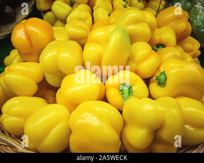 Fresh yellow peppers on a wicker plate in the store with lens flare. For any purprose. Stock Photo