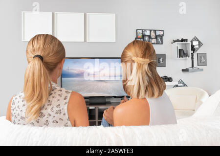 Young women sitting on couch enjoying watching television at home Stock Photo