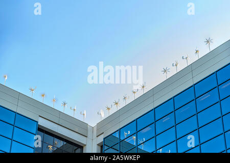 Wind turbines producing energy on top of modern office building on a very windy day Stock Photo