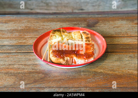 Toast topped with red jam and toast covered with butter and sugar on a zinc coated tray for food that on a wooden table Stock Photo