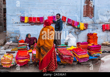 A man selling textiles to a customer at an open air street market in Jodhpur, Rajasthan, India. Stock Photo
