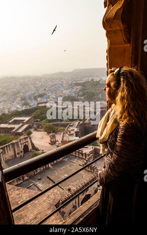 Woman looks out the window of an flying airplane. Young caucasian happy ...