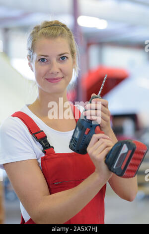 female engineer using drill in factory Stock Photo