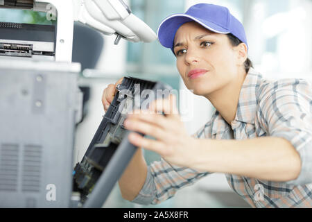 young woman fixing a printer Stock Photo