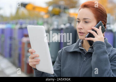 young woman in uniform using mobile phone and tablet Stock Photo