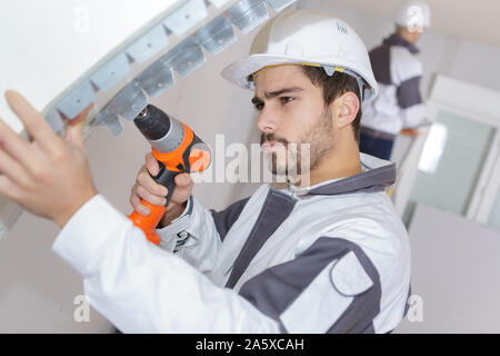 man working with drill indoors Stock Photo