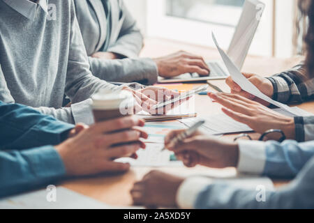 Startupers working together at office having business meeting table close-up browsing devices drinking coffee taking notes Stock Photo