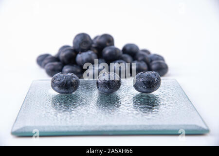 Ripe blueberries - Three big wet and ripe blueberries on a glass plate - Delicious bunch of blueberries - Blueberries close-up Stock Photo