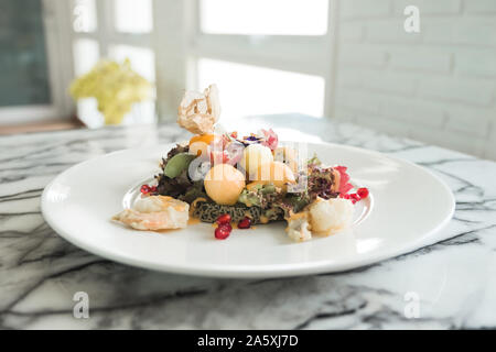 Closeup image of mixed fruits salad with fried shrimps on white plate in the restaurant Stock Photo