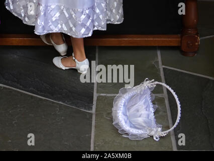 Feet of wedding flower girl taking a break besides a discarded flower basket. Stock Photo