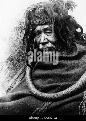 Edward S. Curits Native American Indians - Half-length portrait of Nakoaktok man, facing left, wearing cedar root ceremonial loop ca. 1910 Stock Photo