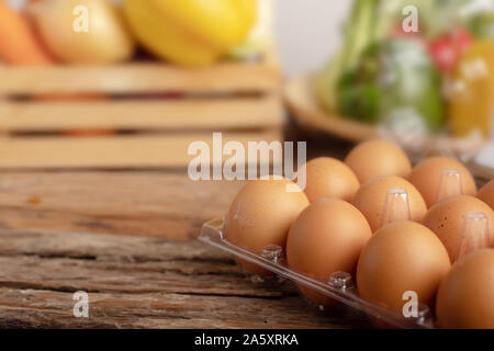 Eggs in the plastic on the wooden table and vegetable in a wood box Stock Photo