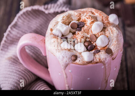 Close-up of a pink mug with lush hot chocolate with whipped cream and pieces of marshmallows and chocolate chips. Stock Photo