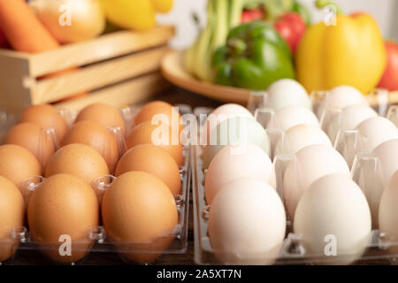 Close up eggs of duck and chicken are placed on a wooden table with various vegetables in wood box. Select focus shallow depth of field and blurred ba Stock Photo