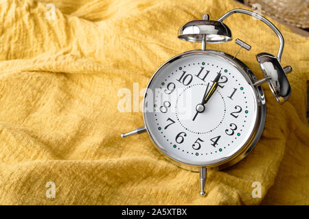 Close up the alarm clock place on the yellow fabric. Abstract background and texturd with the time. Stock Photo
