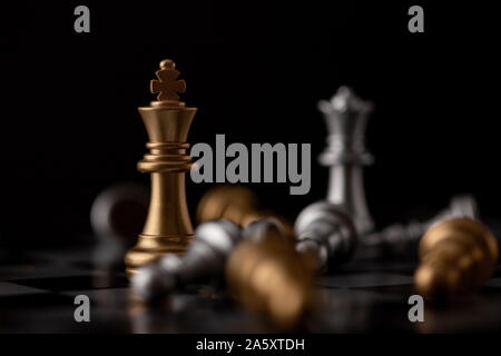 King and Queen standing in the midst of falling chess on board Stock Photo