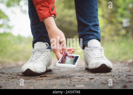 Woman is picking up a mobile phone from a ground closeup. Stock Photo