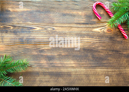 Candy cane Christmas background. Candy red sticks and fir tree branches, space for text, top view. Stock Photo