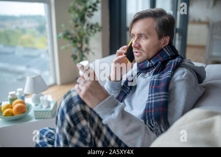Man wearing scarf speaking with doctor on phone Stock Photo