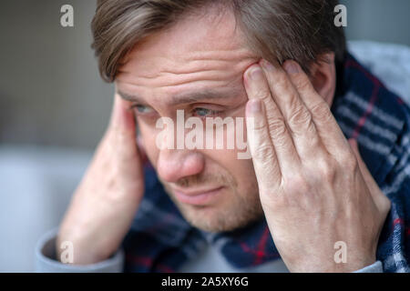 Blue-eyed bearded man feeling terrible while having headache Stock Photo