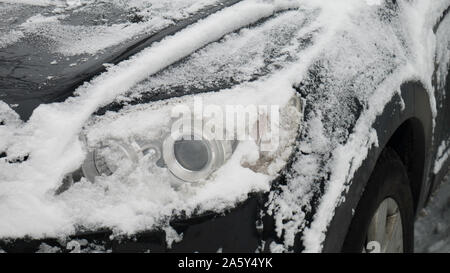 Car lights under the snow. Front icy car headlight. icy headlamp in winter, car fragment. Stock Photo