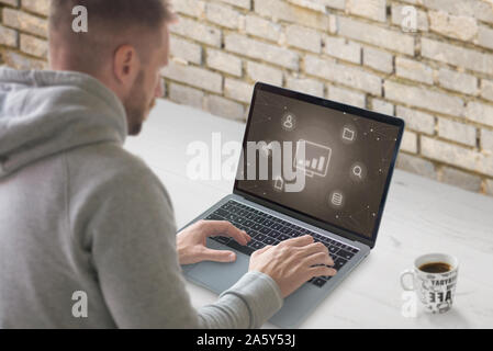 Concept of growth social network marketing industry. Guy work on laptop with conceptual icons. Stock Photo