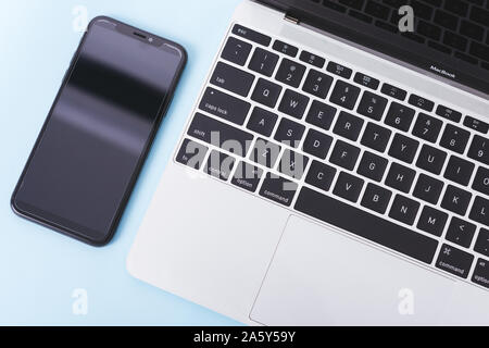 Top view of modern technology smart phone mobile and computer laptop on blue background with copy space Stock Photo
